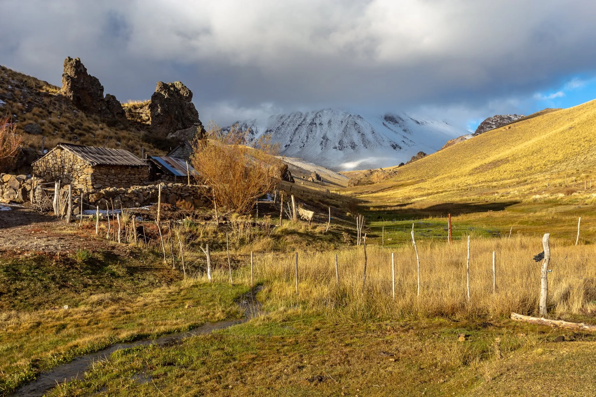 Puesto rural con el volcán Domuyo nevado al fondo