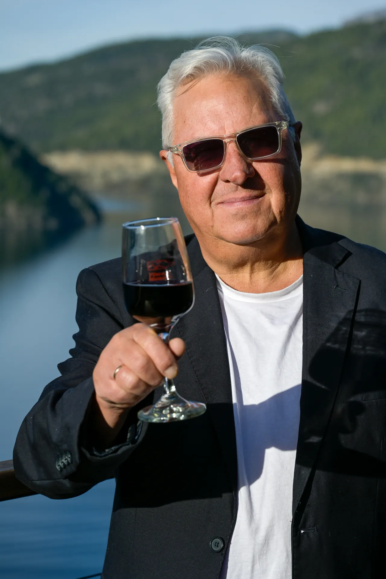 Sergio Landoni con una copa de vino frente a un lago de Patagonia, imagen del artículo en Vinetur sobre vino neuquino