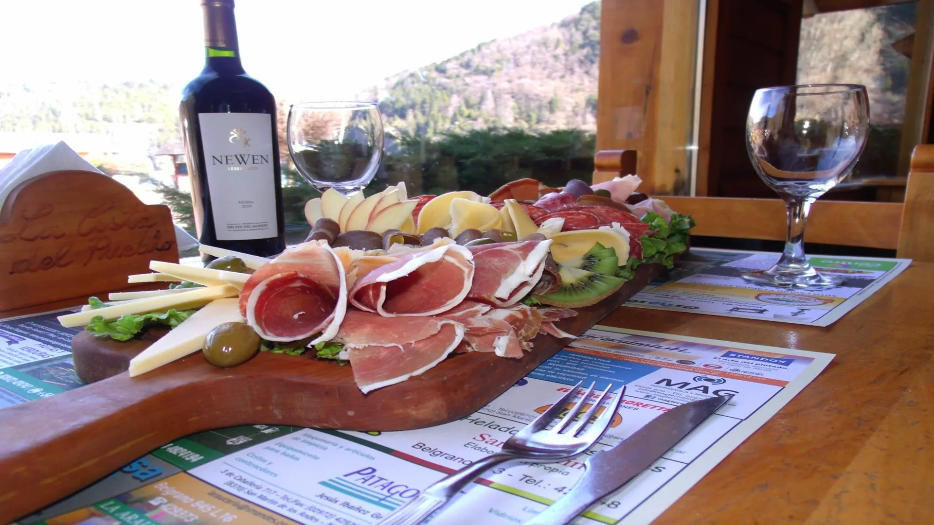 Vino patagónico acompañado con picada regional en mesa de madera